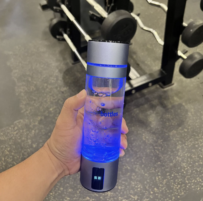 Customer holding the ATOM hydrogen water bottle at the gym